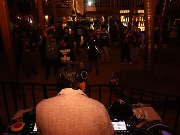 The view from behind the booth over Immortal Baba's shoulder towards a crowd dancing between wooden pillars
